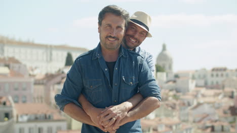 Front-view-of-married-gay-couple-standing-and-hugging-outdoors