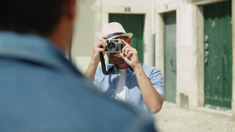 Front-view-of-smiling-man-taking-photo-of-boyfriend-on-camera