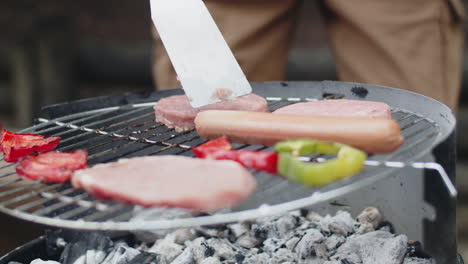 Close-up-of-an-unrecognizable-man-putting-hamburger-patties-on-grill