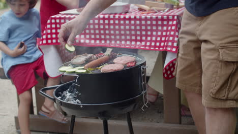 Close-up-of-an-unrecognizable-man-cooking-and-putting-vegetables-on-grill-during-a-family-picnic
