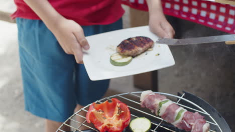 Tracking-shot-of-an-unrecognizable-person-putting-grilled-meat-on-plate