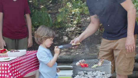 Caring-dad-giving-his-little-son-taste-of-barbeque
