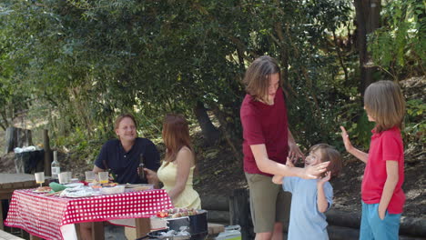 Long-shot-of-happy-brothers-lokking-at-the-camera-and-giving-five-to-each-other-during-a-family-picnic