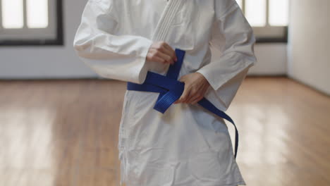Front-view-of-unrecognisable-girl-tying-blue-belt-on-kimono