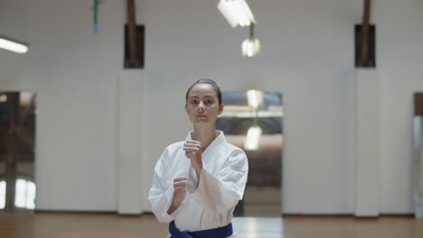 Vista-Frontal-De-Una-Chica-Seria-Realizando-Posturas-Básicas-De-Karate