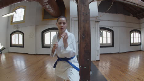 Handheld-shot-of-girl-in-kimono-and-blue-belt-punching-and-kicking-at-camera