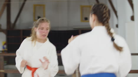 Tiro-De-Mano-De-Chicas-Lindas-En-Kimono-Practicando-Karate-En-El-Gimnasio