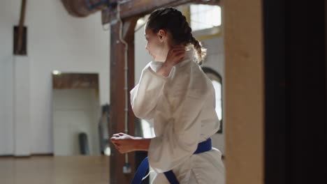 Medium-shot-of-karateka-lunging-and-kicking-in-practice-room