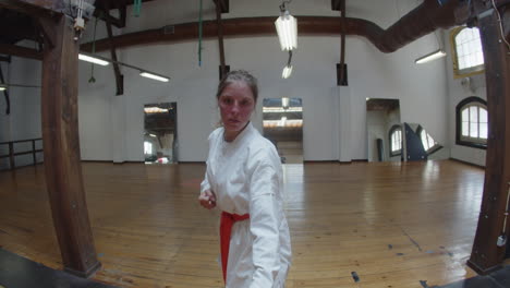 Handheld-shot-of-focused-girl-showing-karate-movements-in-gym