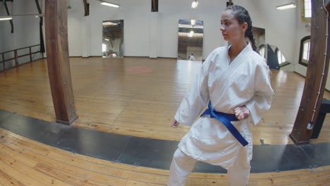 Tiro-De-Seguimiento-De-Chica-Enfocada-Practicando-Movimientos-De-Karate-En-El-Gimnasio