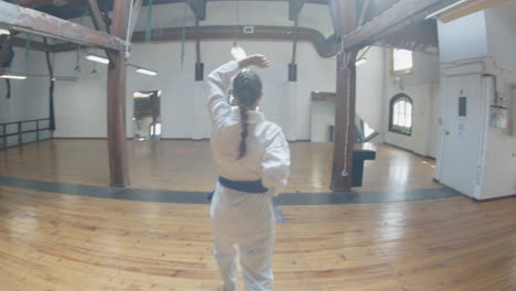 Chica-Enfocada-Demostrando-Movimientos-De-Karate-En-La-Sala-De-Práctica