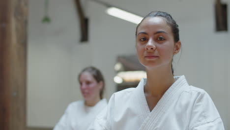 Close-up-shot-of-karateka-smiling-at-camera-while-sitting-in-gym