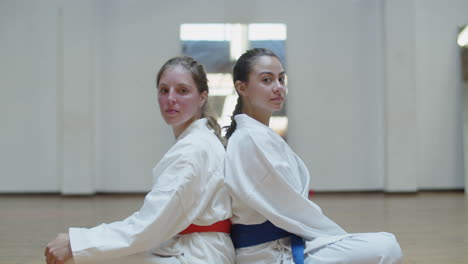 Vertical-motion-of-girls-in-kimonos-sitting-back-to-back-in-gym