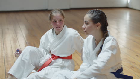 Handheld-shot-of-girls-sitting-on-floor-after-karate-workout