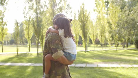 Soldier-dad-carrying-daughter-in-arms-in-the-park