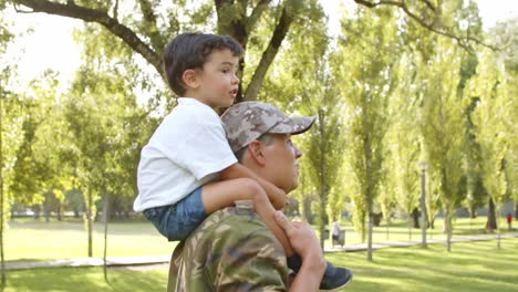 Happy-little-boy-riding-dad's-shoulders-in-park