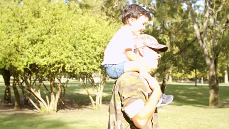 Excited-little-boy-riding-dad's-shoulders-in-park