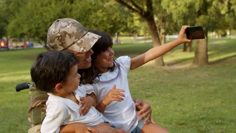 Feliz-Padre-Militar-Discapacitado-En-Silla-De-Ruedas-Y-Dos-Niños-Hablando-Selfie