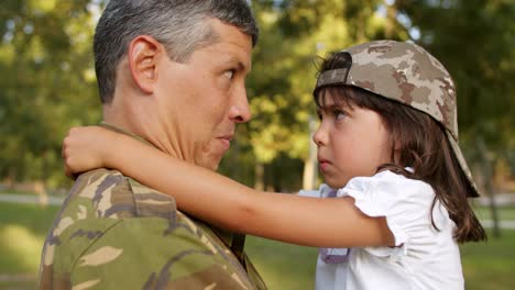 Happy-military-dad-putting-camouflage-cap-on-daughter