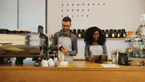 Caucasian-barista-with-beard-and-african-young-woman-working-in-trendy-coffee-shop