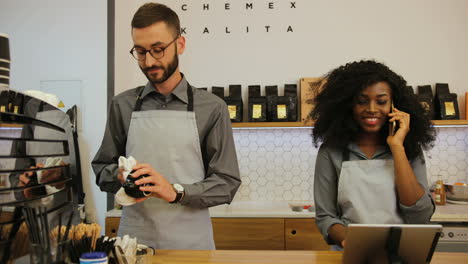 Caucasian-barista-with-beard-and-african-american-young-woman-working-in-trendy-coffee-shop