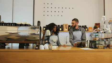 Caucasian-man-with-beard-and-african-american-young-female-barista-working-in-modern-coffee-shop