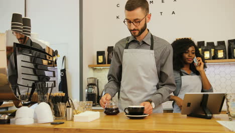 Caucasian-male-barista-and-caucasian-female-coworker-working-in-modern-coffee-shop