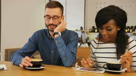 Young-caucasian-man-drinking-coffee-with-african-american-woman-in-stylish-cafe