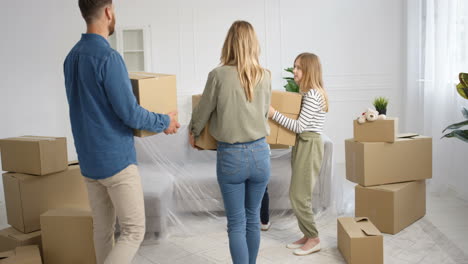 Caucasian-happy-family-with-kids-carrying-carton-boxes-in-new-home