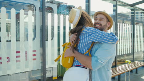 Happy-Caucasian-young-couple-meeting-at-train-station-and-hugging-on-nice-summer-day