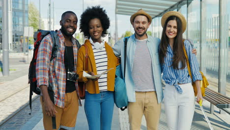 Multiethnic-group-of-friends-travellers-smiling-and-looking-at-the-camera-at-train-station