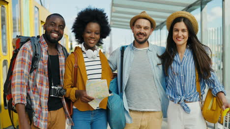 Multiethnic-group-of-friends-travellers-smiling-and-looking-at-the-camera-at-train-station