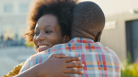 Close-up-view-of-happy-african-american-young-couple-meeting-at-train-station-and-hugging-on-nice-summer-day