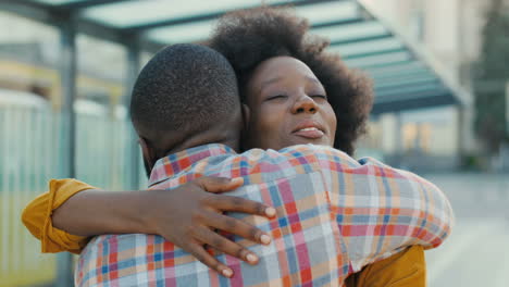 Close-up-view-of-happy-african-american-young-couple-meeting-at-train-station-and-hugging-on-nice-summer-day