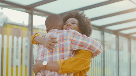 Happy-african-american-young-couple-meeting-at-train-station-and-hugging-on-nice-summer-day