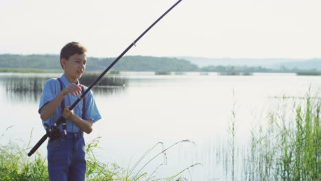 Teen-boy-fishing-on-the-lake-and-catching-a-fish-with-the-rod