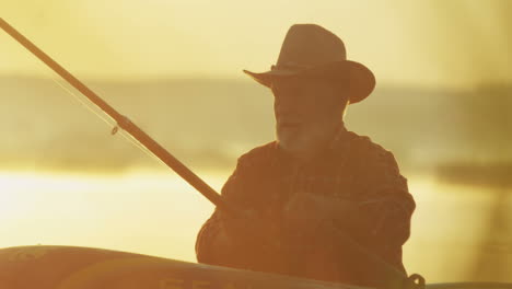 Close-up-view-of-a-senior-caucasian-man-floating-with-oars-in-a-boat-in-the-dawn-in-the-middle-of-the-lake