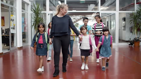 Escolares-Multiétnicos-Caminando-En-El-Pasillo-Con-Una-Maestra