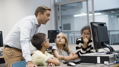 Computer-science-teacher-discussing-task-with-schoolchildren