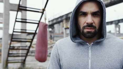 Close-up-view-of-handsome-man-with-grey-hoodie-and-looking-with-serious-expression-at-the-camera