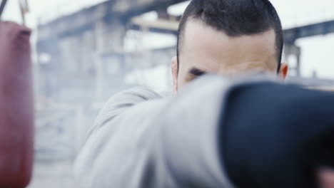 Close-up-view-of-handsome-bearded-caucasian-man-boxing-to-the-camera-outdoors-an-abandoned-factory-on-a-cloudy-morning