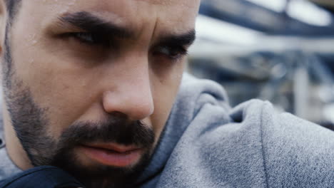 Close-up-view-of-the-sweaty-face-of-the-male-boxer-during-a-training-outdoors-an-abandoned-factory-on-a-cloudy-morning