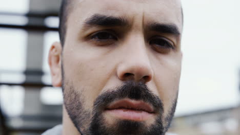 Close-up-view-of-handsome-bearded-sportsman-looking-with-serious-expression-at-the-camera-on-a-cloudy-morning