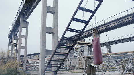 Abandoned-industrial-factory-ruins-with-a-red-punching-bag-hanging-in-the-middle-on-a-cloudy-morning