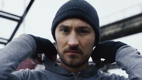 Close-up-view-of-caucasian-bearded-caucasian-man-in-grey-hoodie-and-boxing-to-the-camera-outdoors-an-abandoned-factory-on-a-cloudy-morning