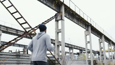 Rear-view-of-a-young-sportsman-in-grey-hoodie-jogging-in-a-old-factory-ruins-on-a-cloudy-morning