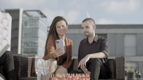 Front-view-of-cheerful-coworkers-looking-at-phone-screen