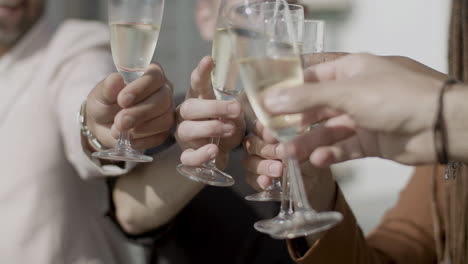 Close-up-shot-of-peoples-hands-clinking-glasses-of-champagne