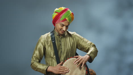Porträt-Eines-Jungen-Fröhlichen-Indischen-Mannes-In-Traditioneller-Kleidung-Und-Turban,-Der-Einen-Schlagzeuger-Spielt-Und-In-Die-Kamera-Lächelt