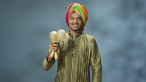 Nahaufnahme-Eines-Fröhlichen-Indischen-Mannes-In-Traditioneller-Kleidung-Und-Turban,-Der-Maracas-Spielt-Und-In-Die-Kamera-Lächelt